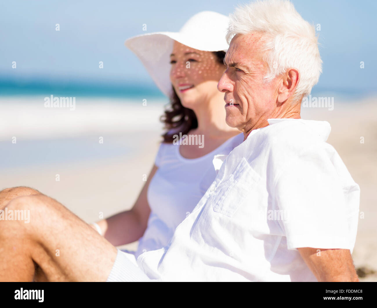 Couple sitting on the beach Stock Photo - Alamy