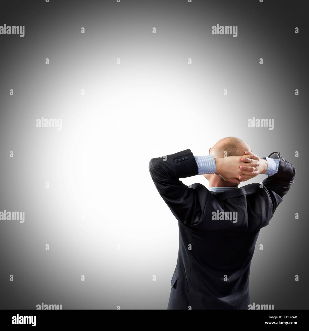 Back view image of businessman with arms crossed behind head. Place for