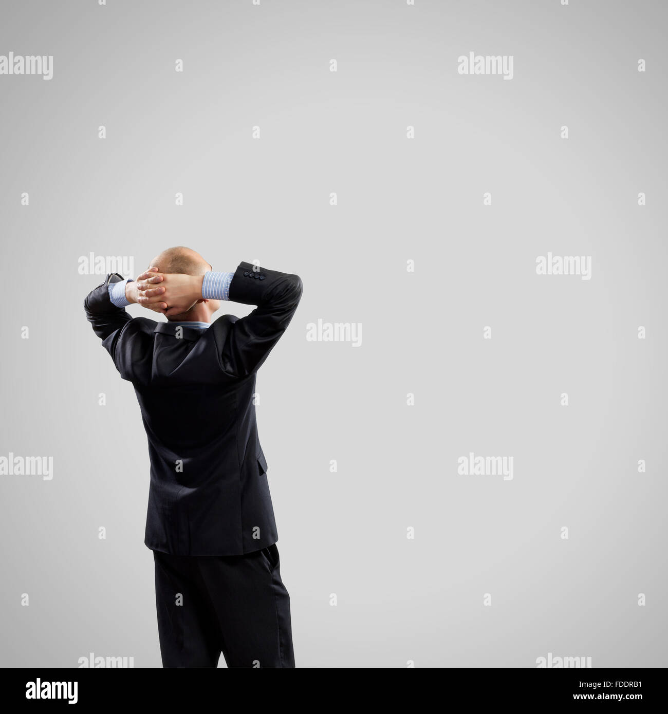 Back view image of businessman with arms crossed behind head. Place for