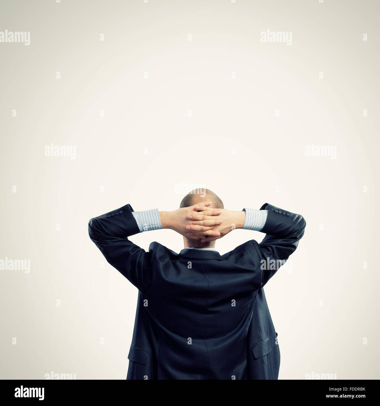 Back view image of businessman with arms crossed behind head. Place for