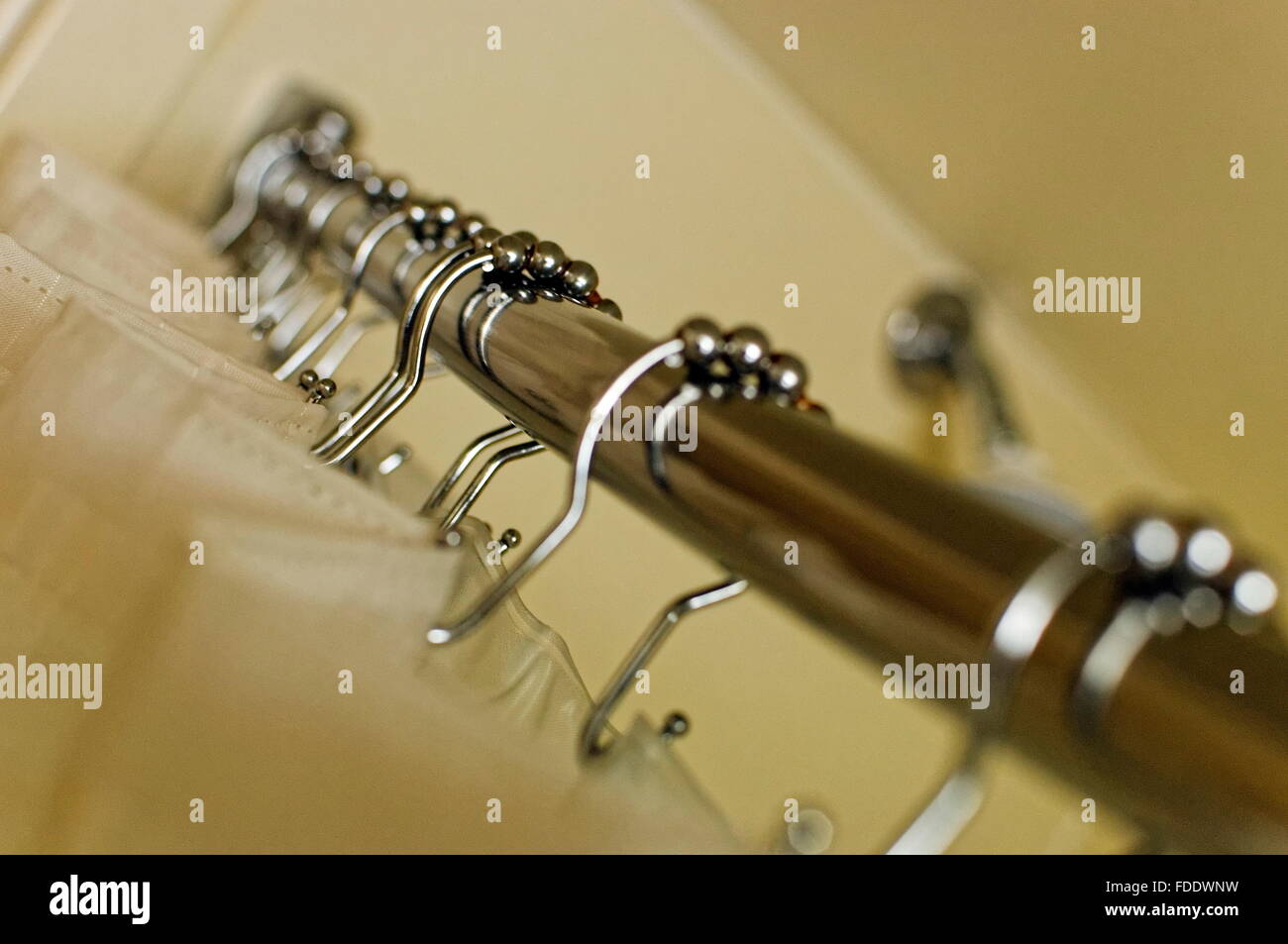 Angled view of white shower curtain on steel rod and held by steel
