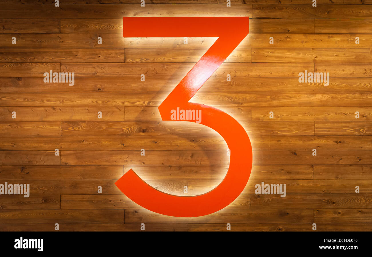 A glowing number 3 against a wood paneled wall at SCAD Atlanta. Stock Photo