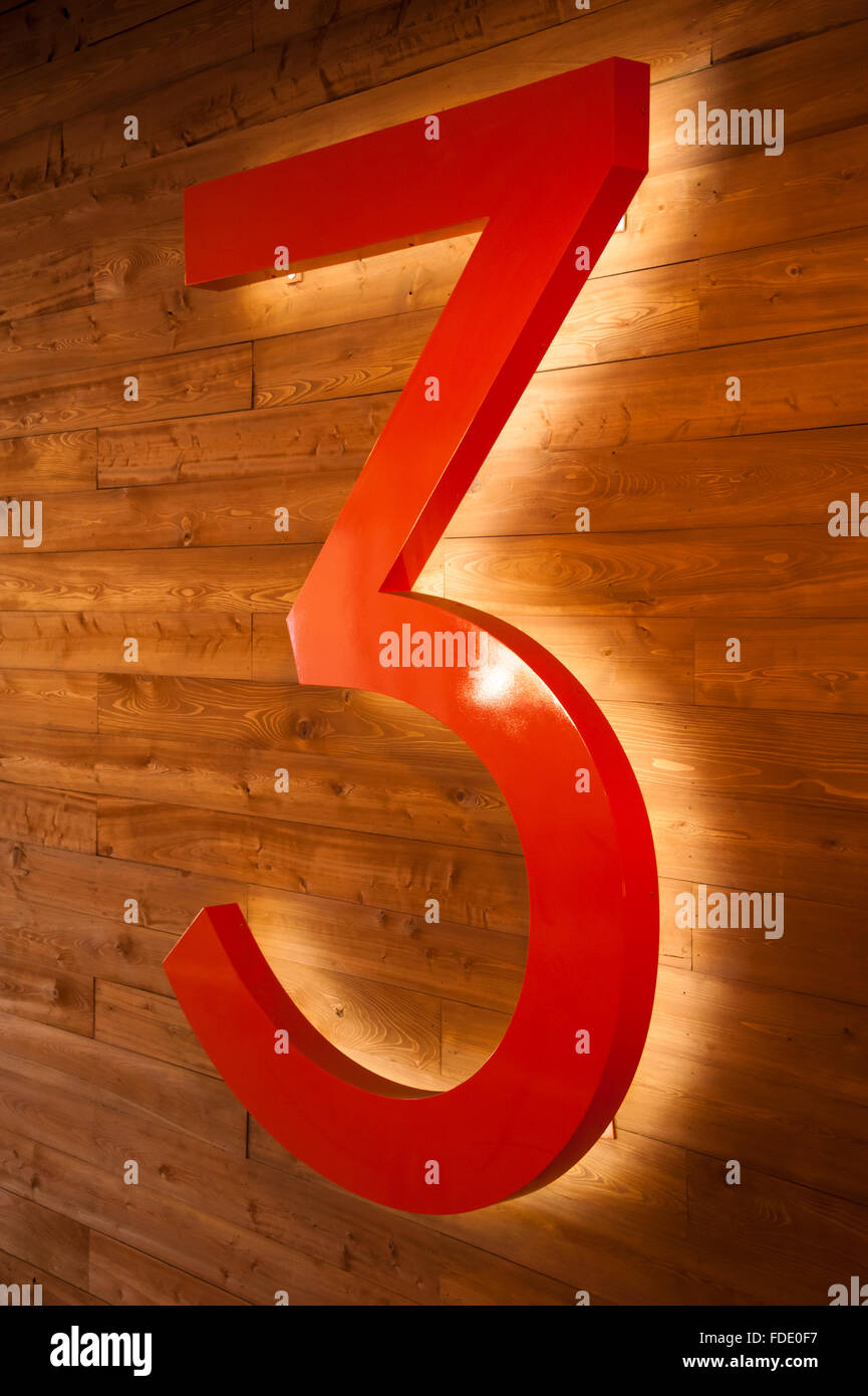 Perspective view of a glowing number 3 against a wood paneled wall at SCAD Atlanta. Stock Photo