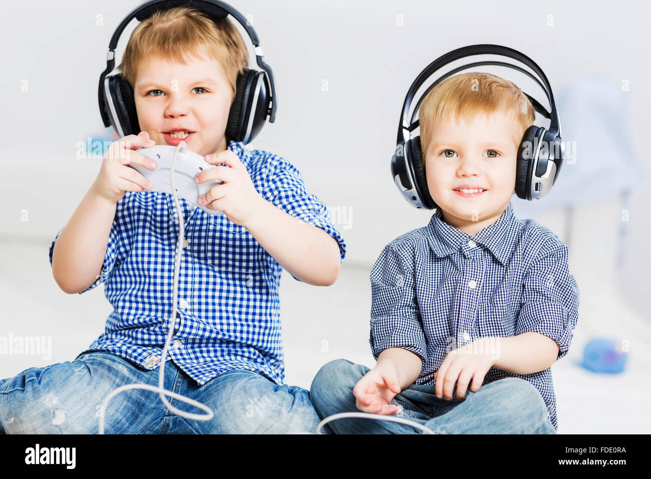 Cute boys playing game in wireless headphones Stock Photo - Alamy