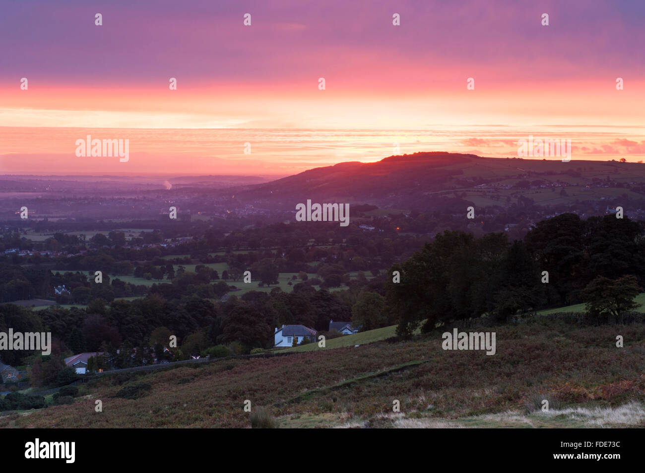 Long distance view over the Wharfe Valley, Yorkshire, England, GB, UK, from high on Burley Moor at sunrise, with a dramatic pink, red and orange sky. Stock Photo