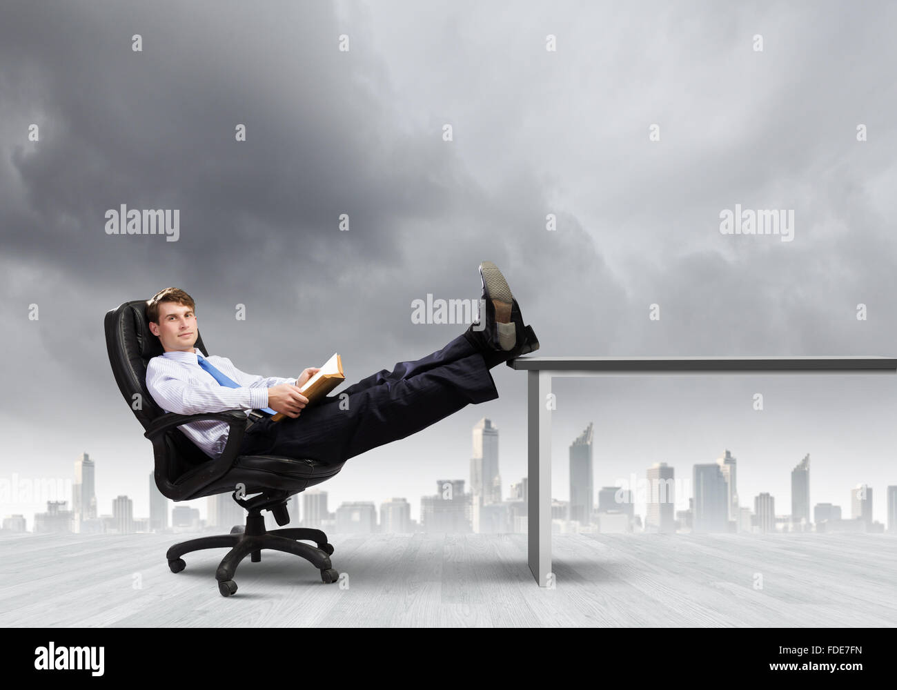 Smiling businessman sitting in chair with legs on table Stock Photo - Alamy