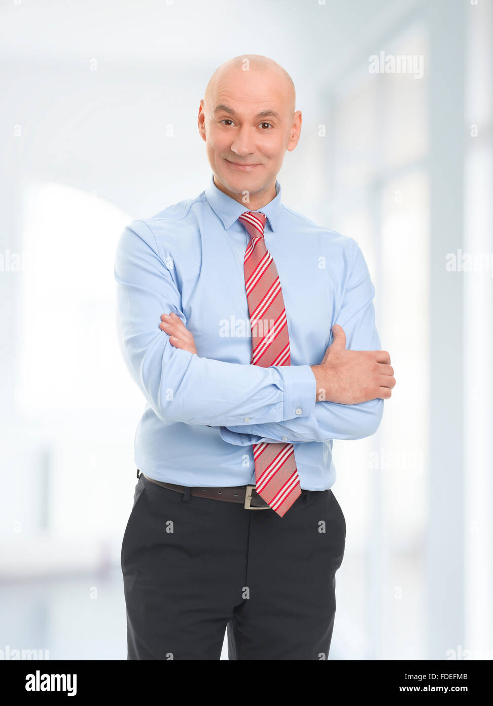 Portrait of successful businessman standing with arms crossed at office ...