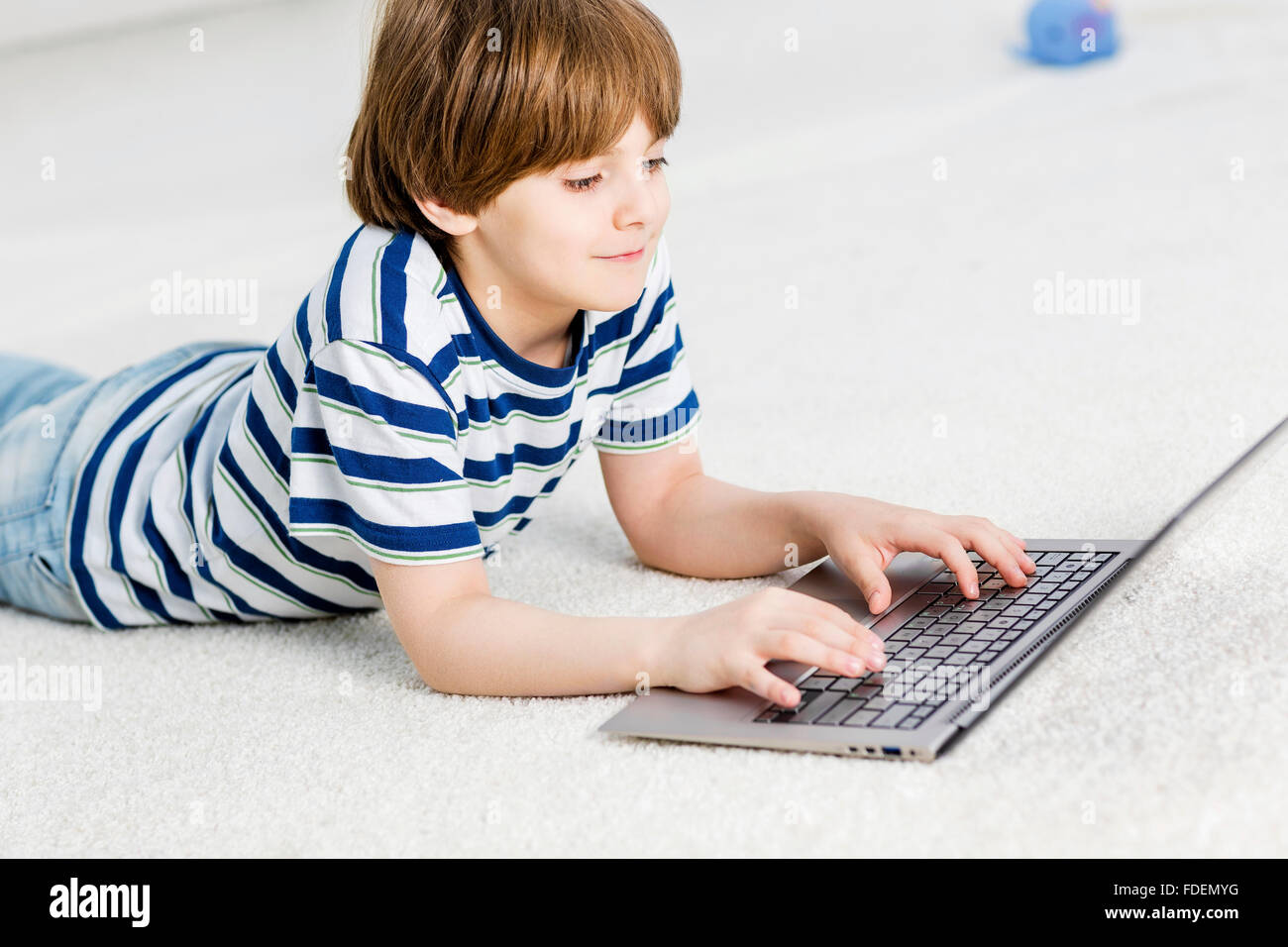Cute boy lying on floor and using laptop Stock Photo - Alamy