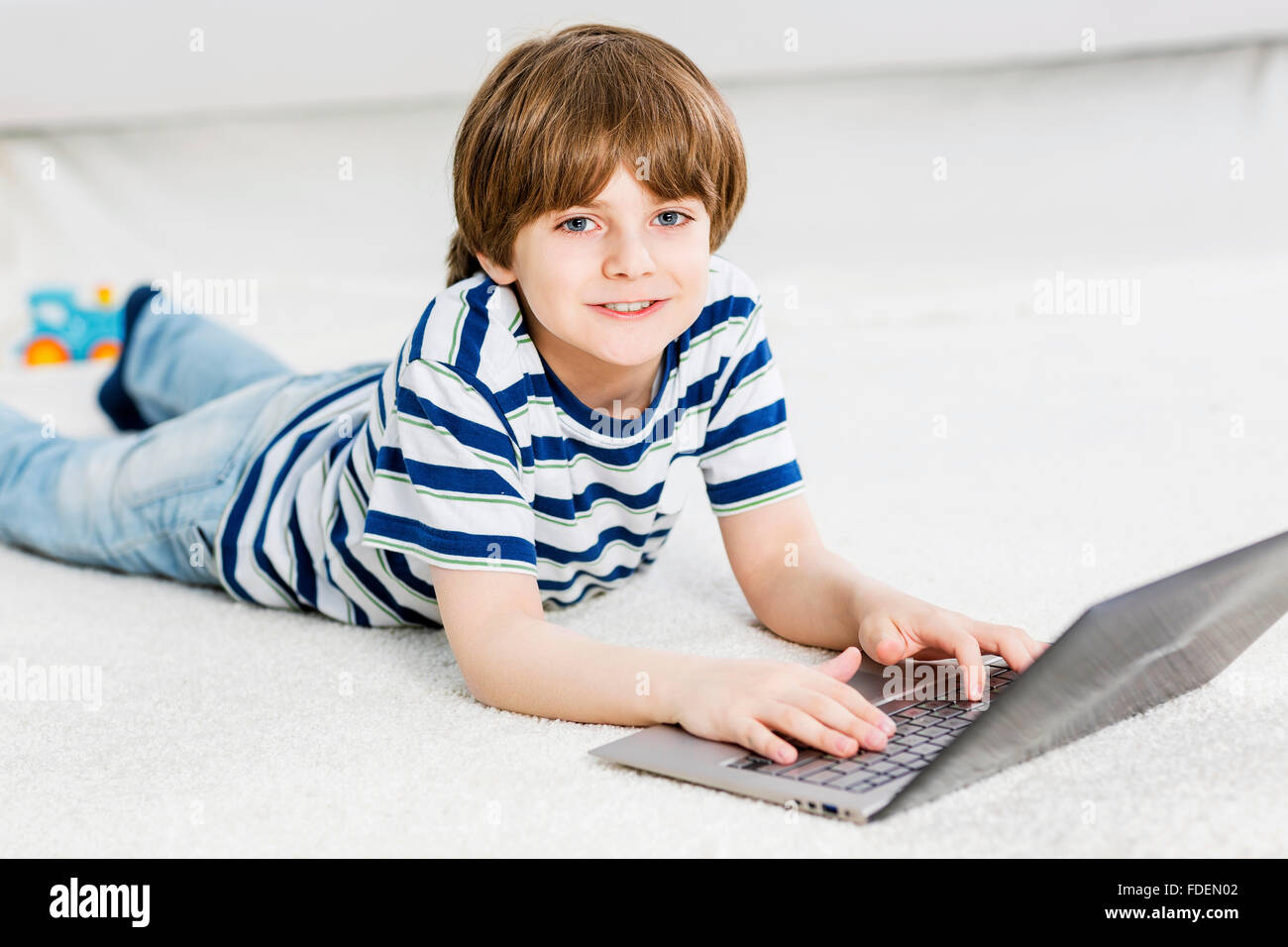 Cute boy lying on floor and using laptop Stock Photo - Alamy
