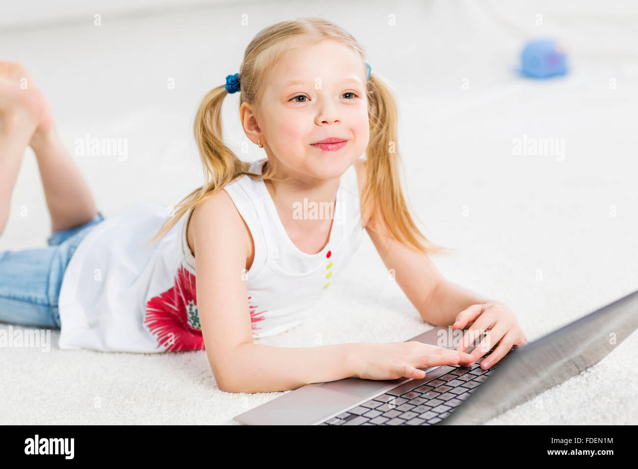 Cute girl laying on the floor and play at laptop Stock Photo - Alamy