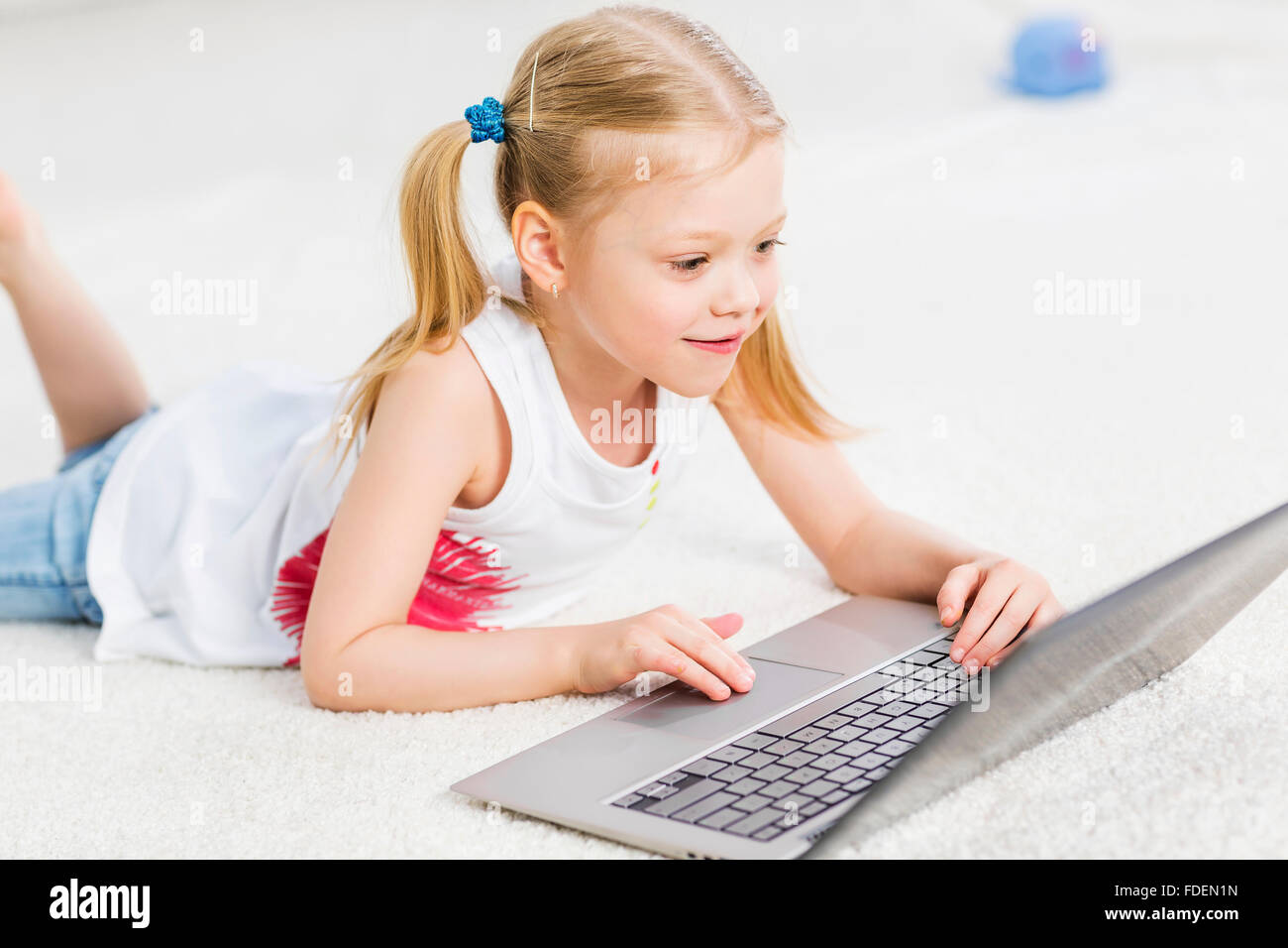 Cute girl laying on the floor and play at laptop Stock Photo - Alamy