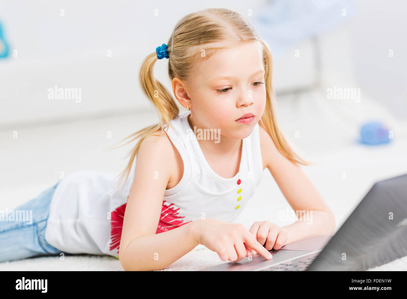 Cute girl laying on the floor and play at laptop Stock Photo - Alamy