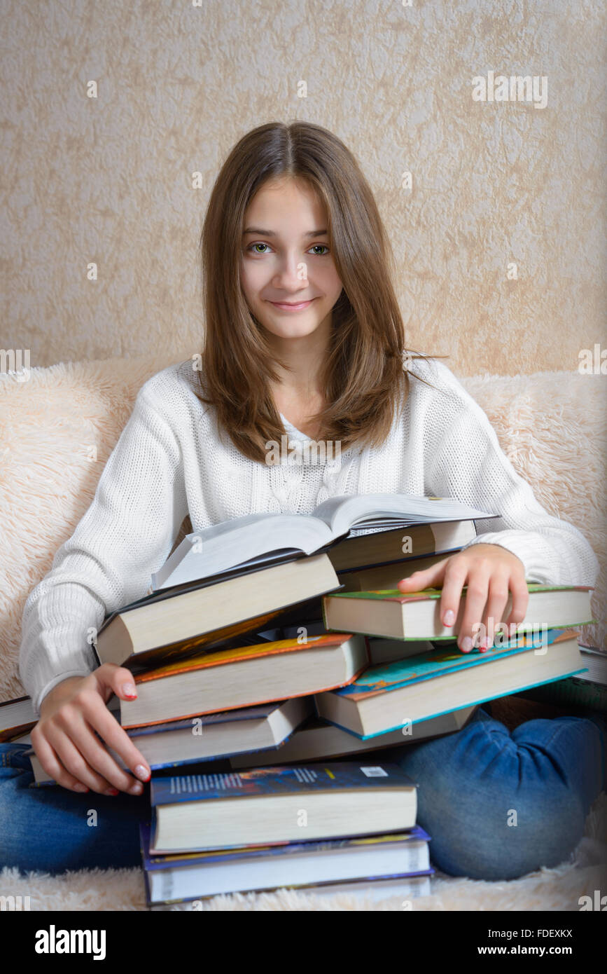 Girl with books sitting on the couch with a fur coverlet Stock Photo