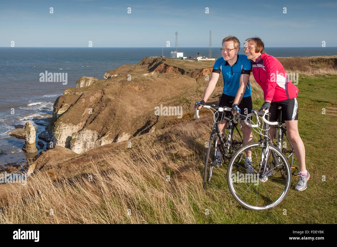Couple looking out to sea with cycles on cliff-top at Flamborough Head, Yorkshire, UK.cliffs and sea in background. Stock Photo
