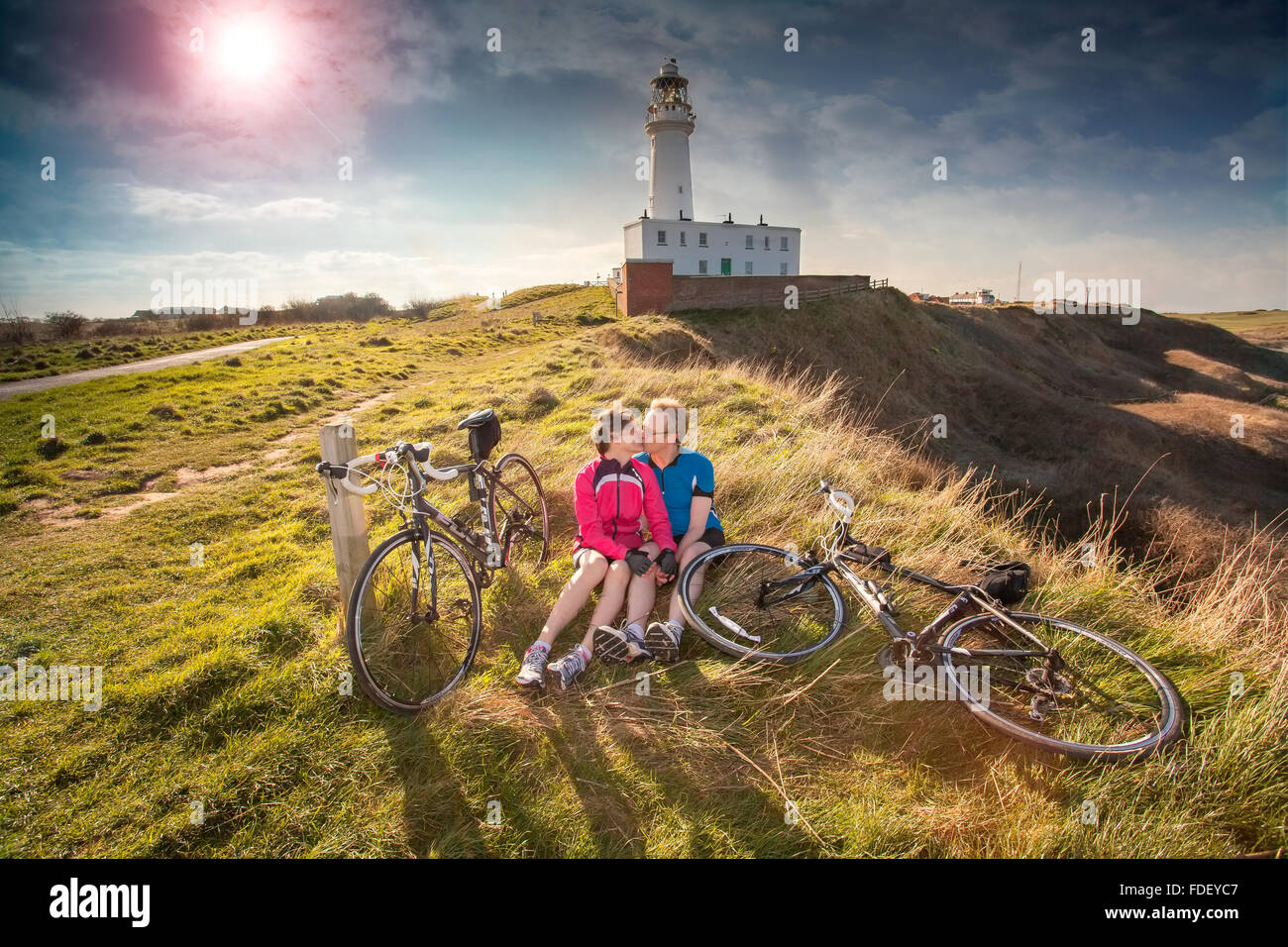 Couple kissing with cycles at Flamborough Head, Yorkshire, UK. Lighthouse is in  background. Stock Photo