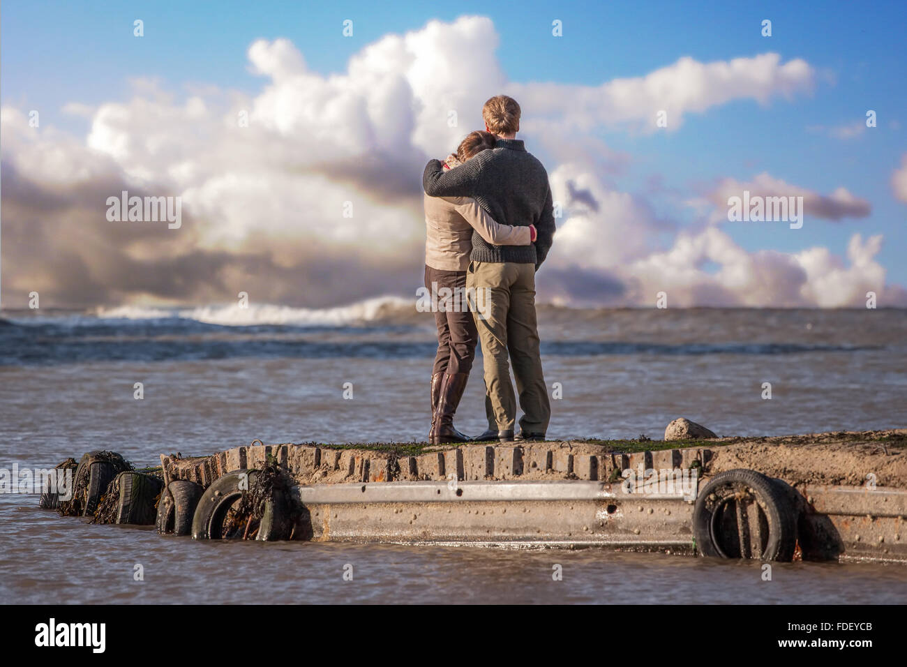 Couple hugging on jetty at Flamborough Head, Yorkshire,  with nice clouds. Good picture for contemplating future life together . Stock Photo