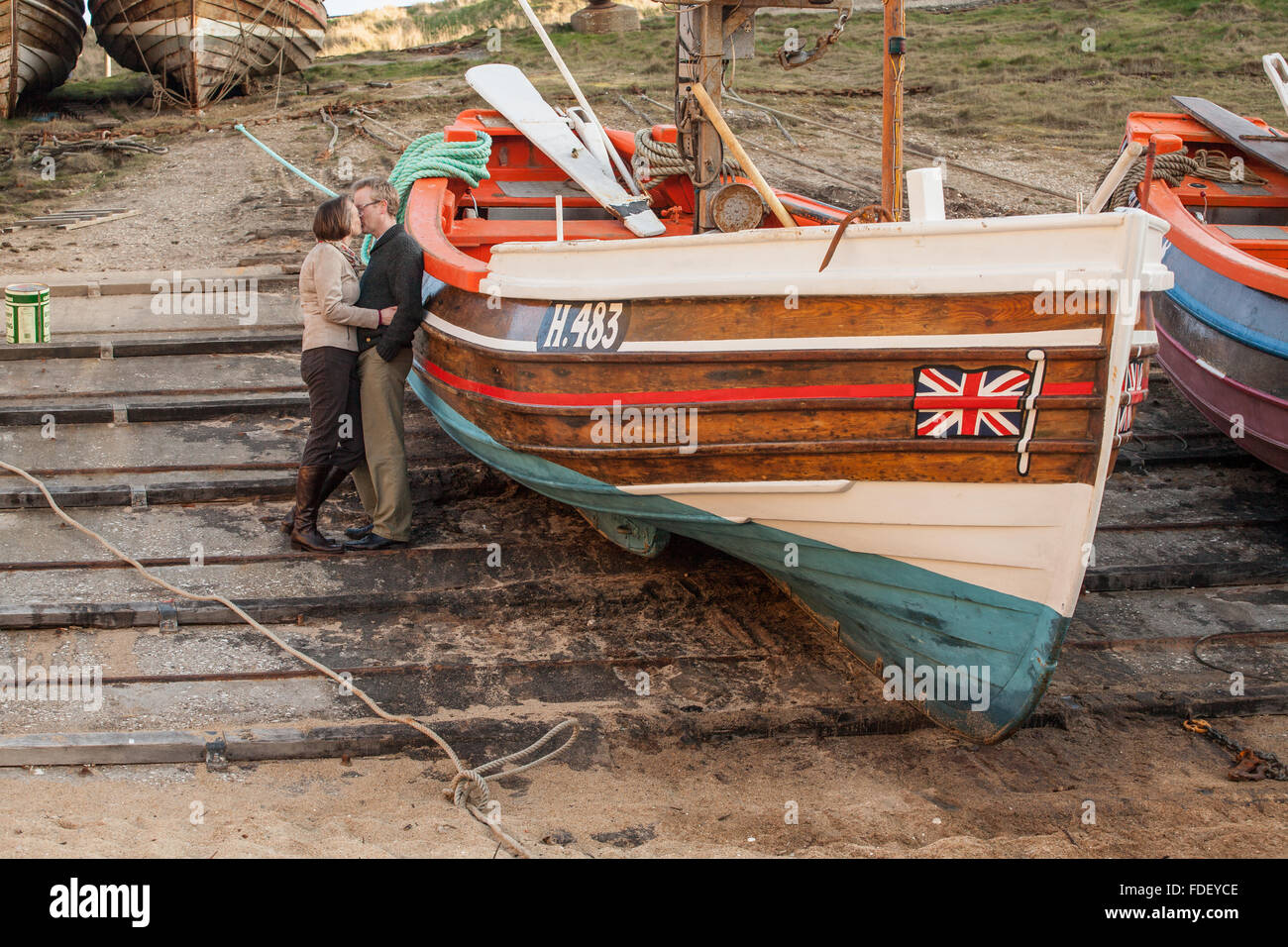 Couple kissing on slipway by boat at Flamborough Head, Yorkshire, UK. Stock Photo