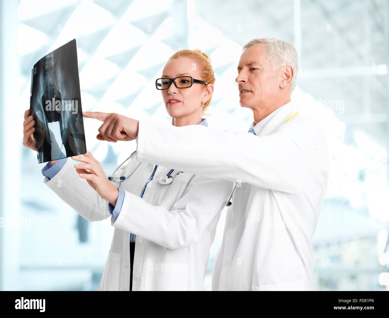 Male doctor shows the problem areas on a X-ray to his colleagues at private clinic. Stock Photo