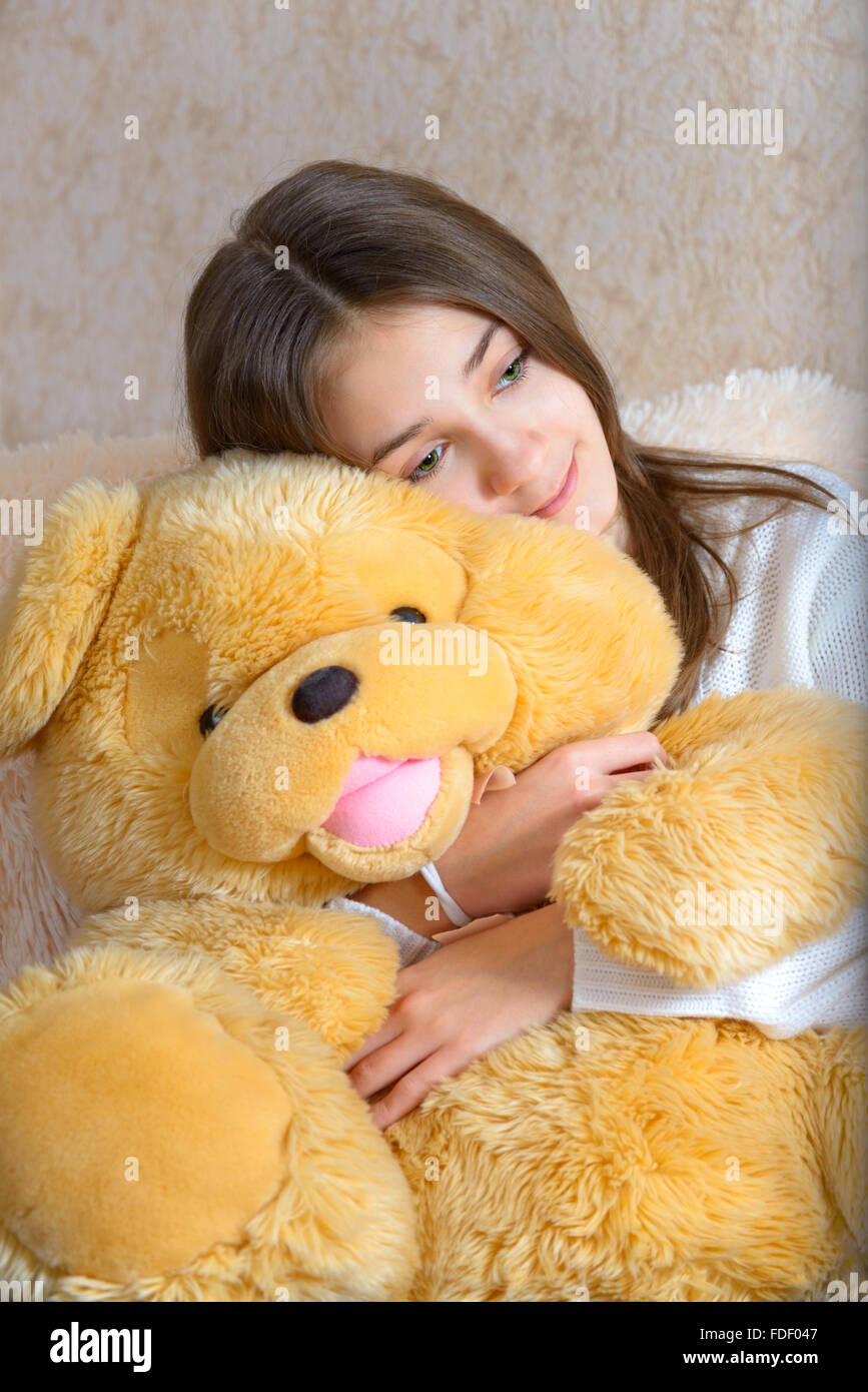 Girl with toy sitting on the couch with a fur coverlet Stock Photo