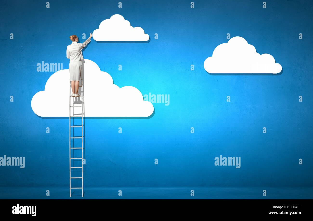 Back view of businesswoman standing on ladder and reaching to cloud ...