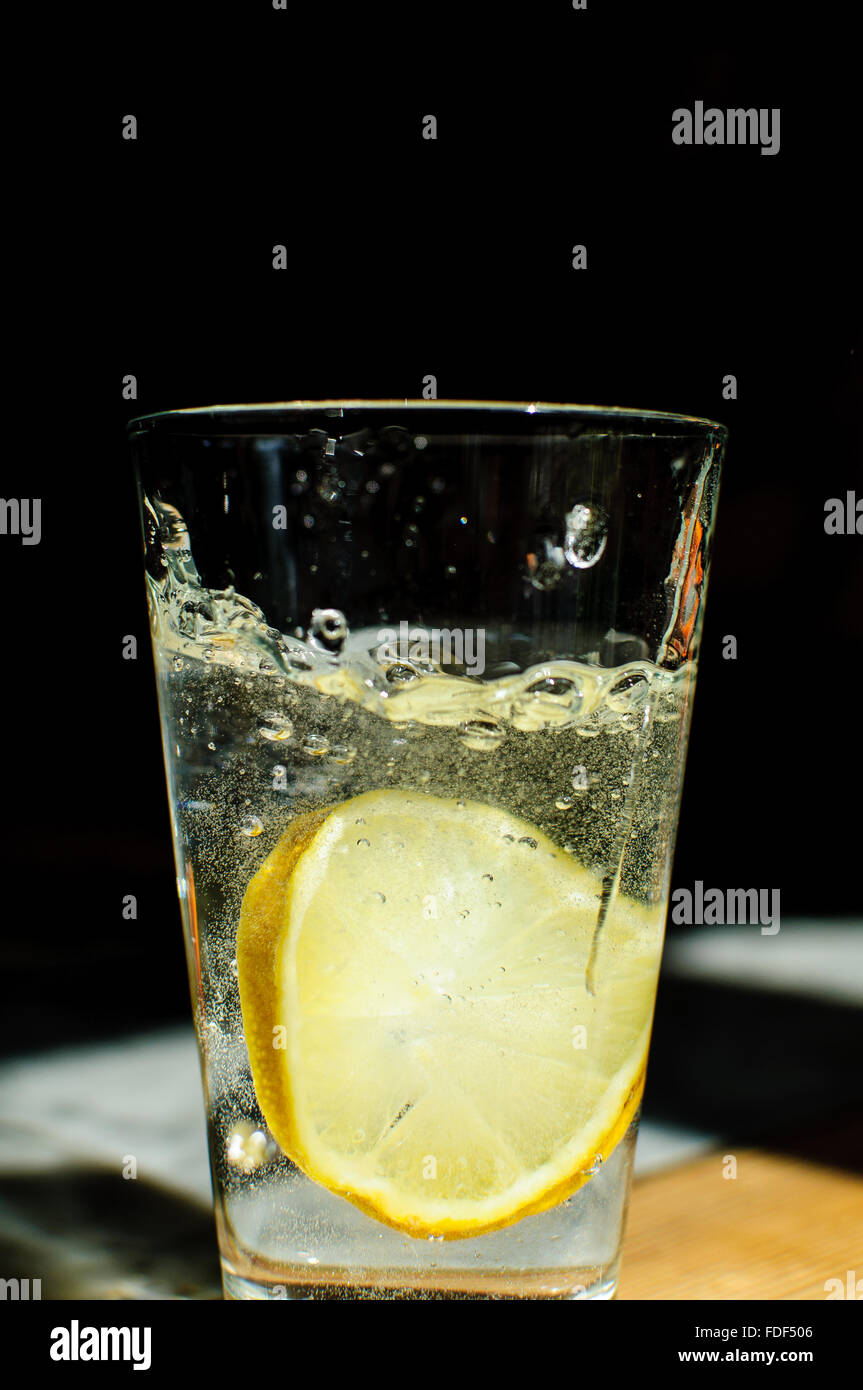 A slice of lemon fallen into a glass of water Stock Photo
