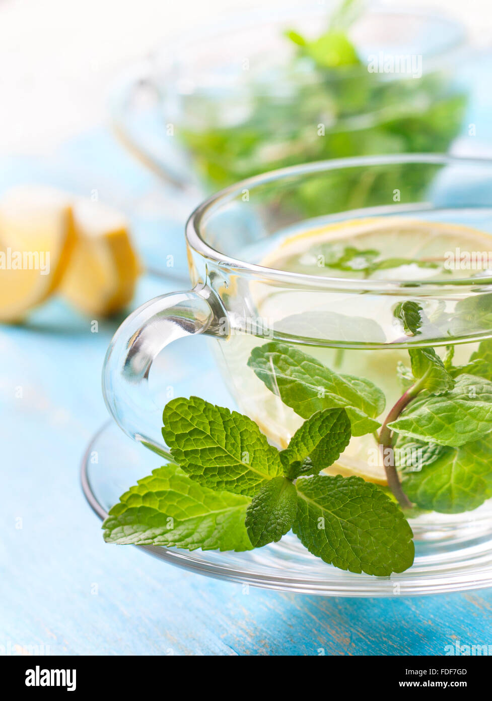 cups of tea with fresh mint and lemon slices on a blue wooden background Stock Photo