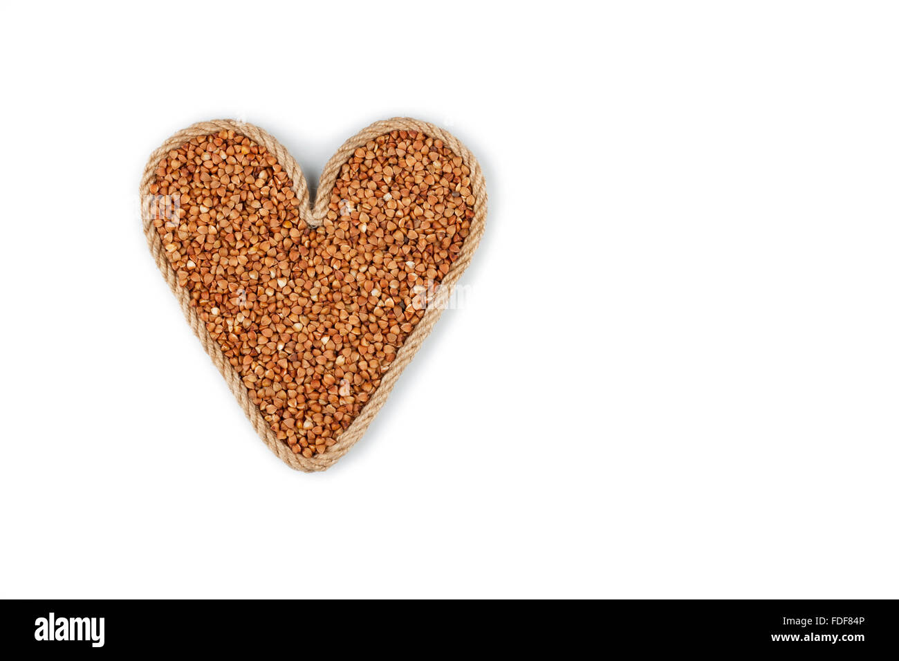 Symbolic heart made from rope with buckwheat grains on a white background Stock Photo