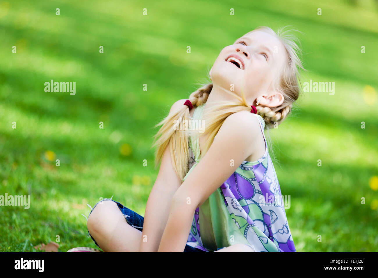 Image of little cute girl sitting on grass in park Stock Photo - Alamy