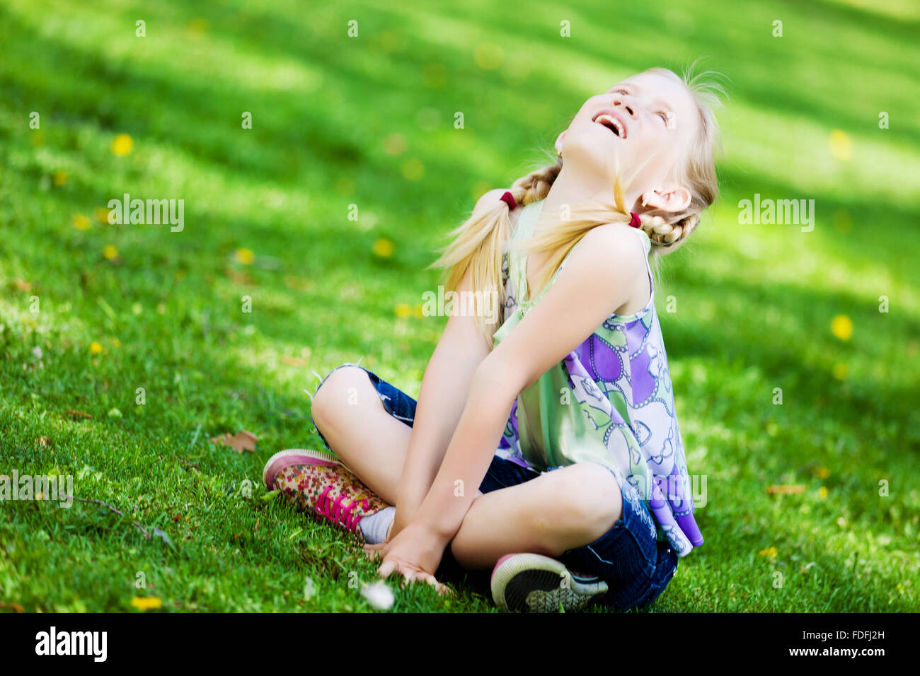 Image of little cute girl sitting on grass in park Stock Photo - Alamy