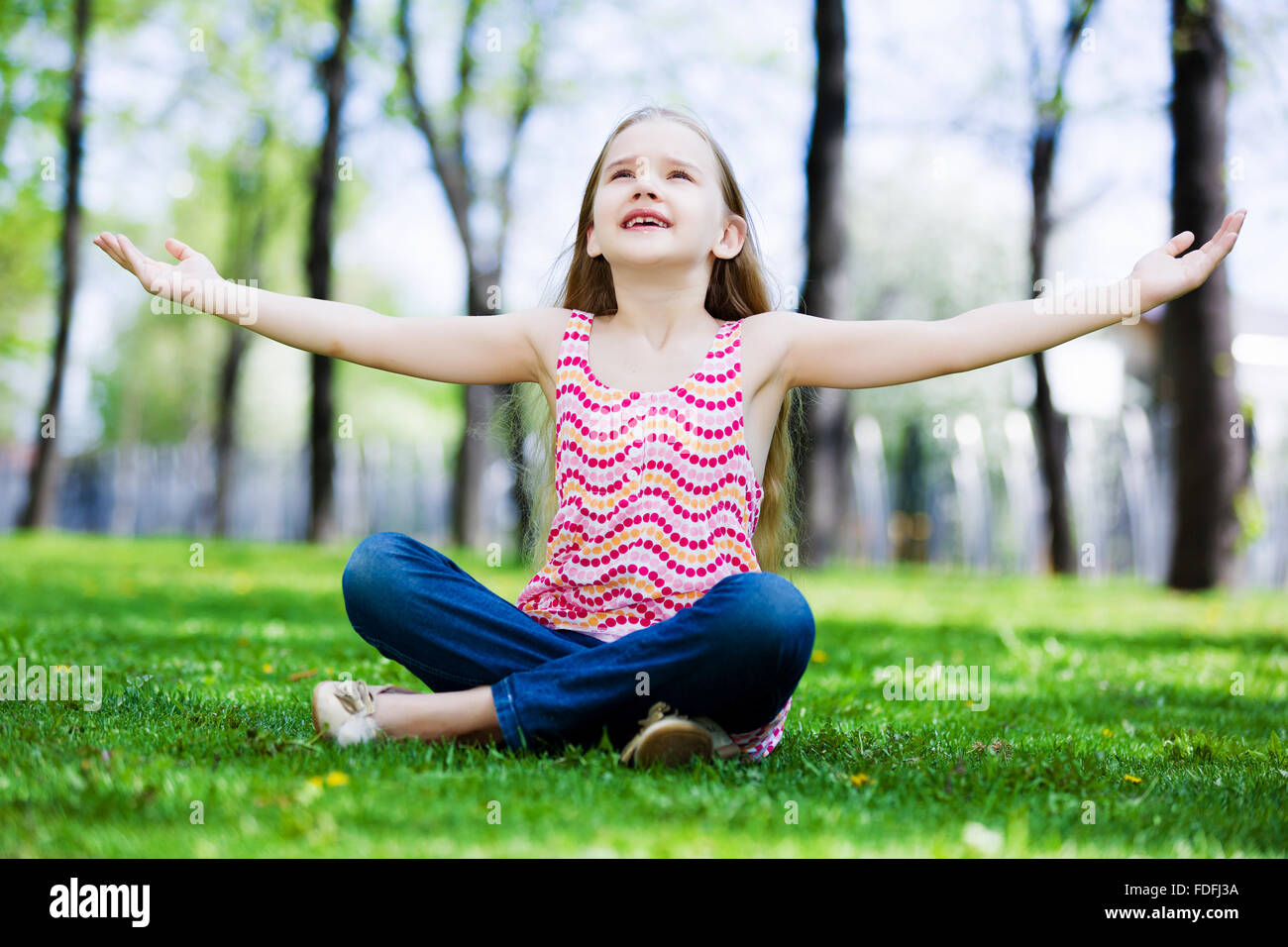 Image of little cute girl sitting on grass in park Stock Photo - Alamy