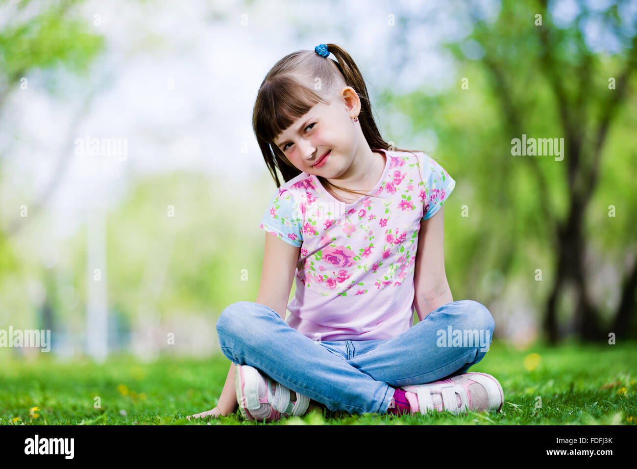 Image of little cute girl sitting on grass in park Stock Photo - Alamy