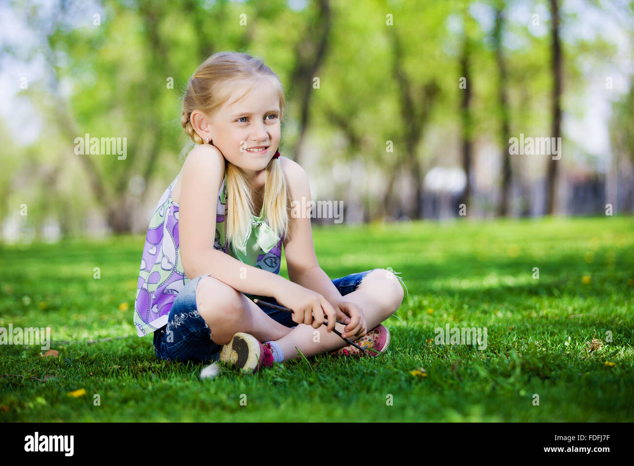Image of little cute girl sitting on grass in park Stock Photo - Alamy