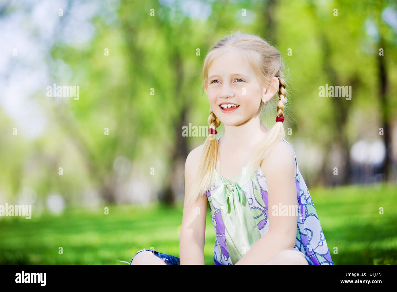 Image of little cute girl sitting on grass in park Stock Photo - Alamy