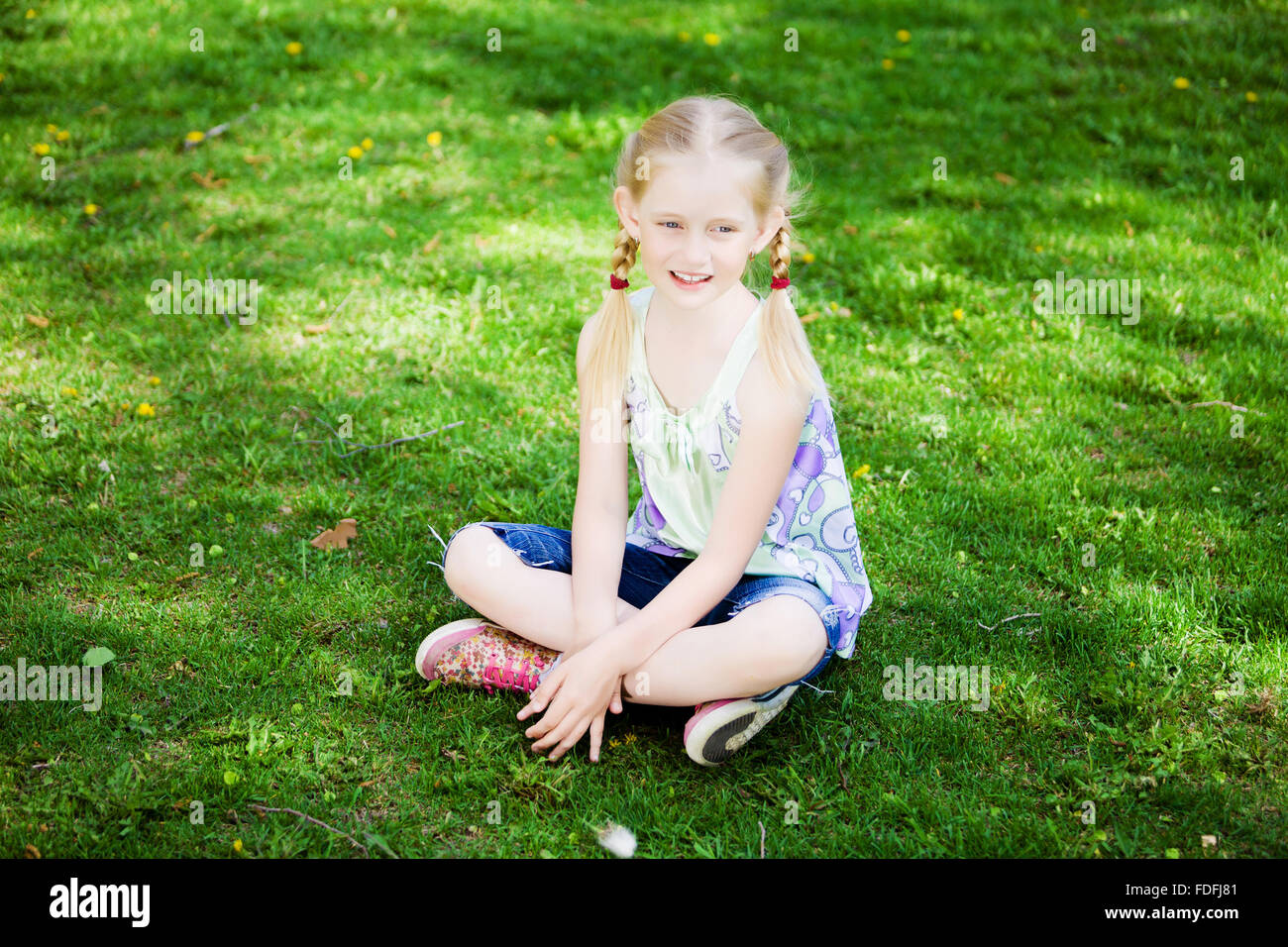 Image of little cute girl sitting on grass in park Stock Photo - Alamy