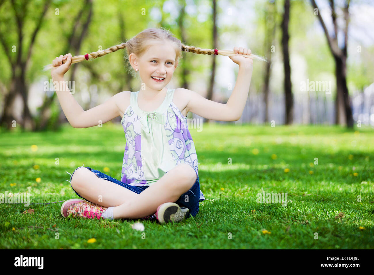 Image of little cute girl sitting on grass in park Stock Photo - Alamy