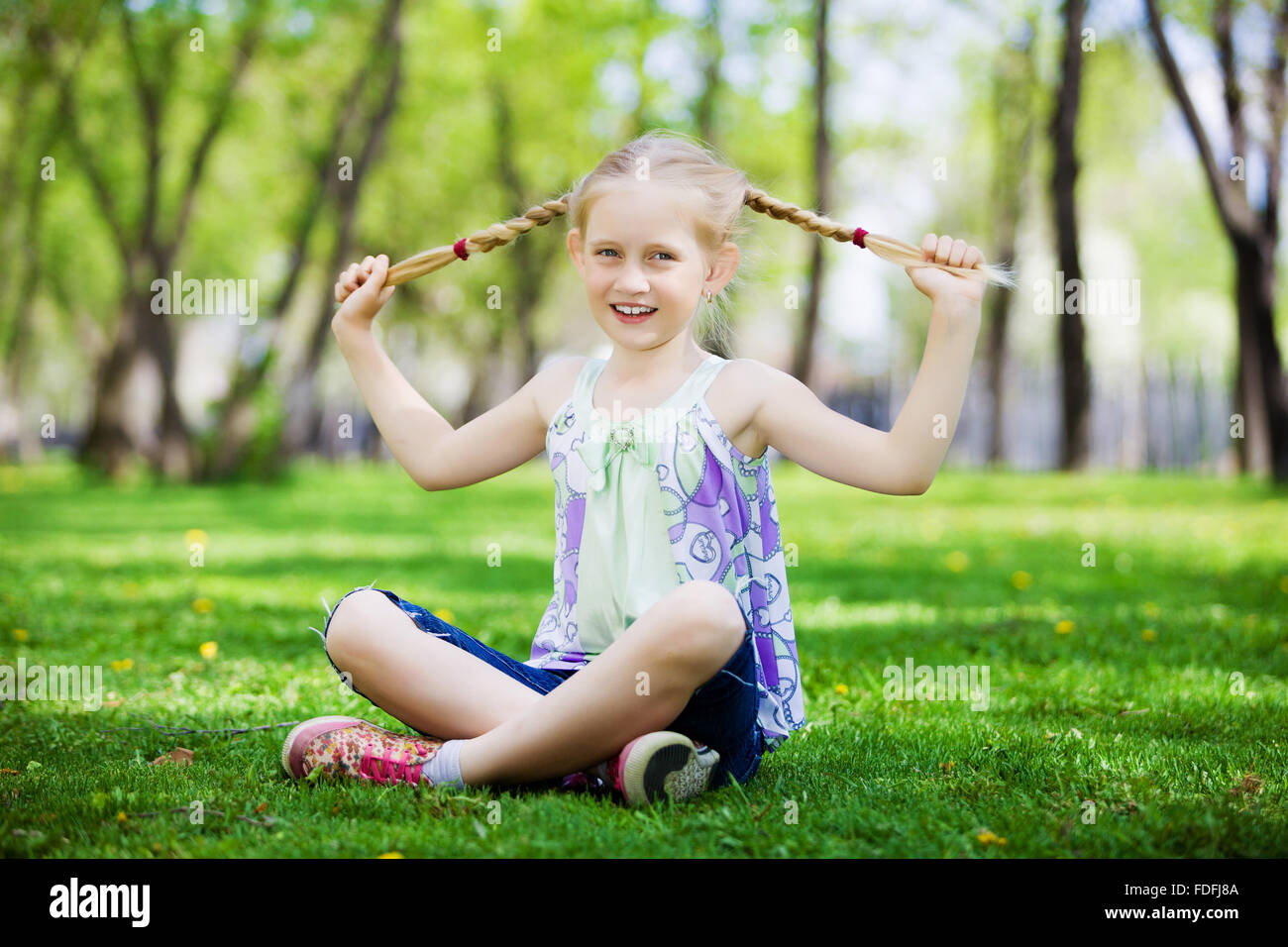 Image of little cute girl sitting on grass in park Stock Photo - Alamy