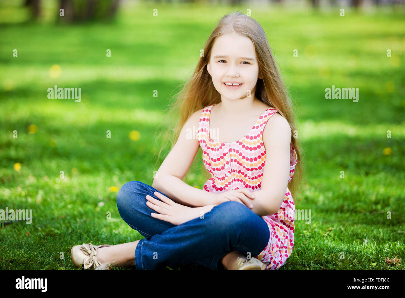 Image of little cute girl sitting on grass in park Stock Photo - Alamy