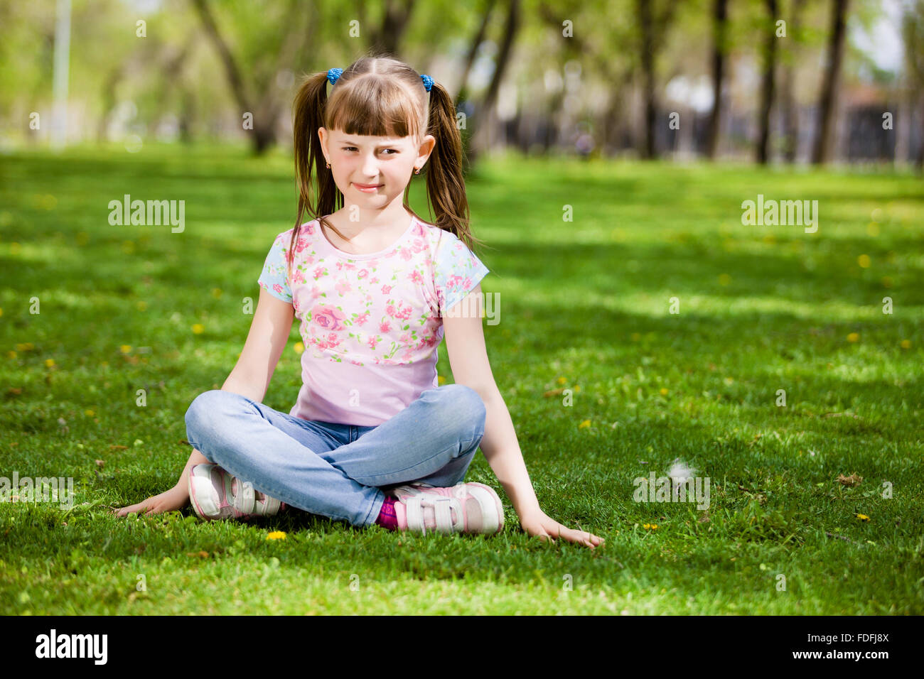Image of little cute girl sitting on grass in park Stock Photo - Alamy