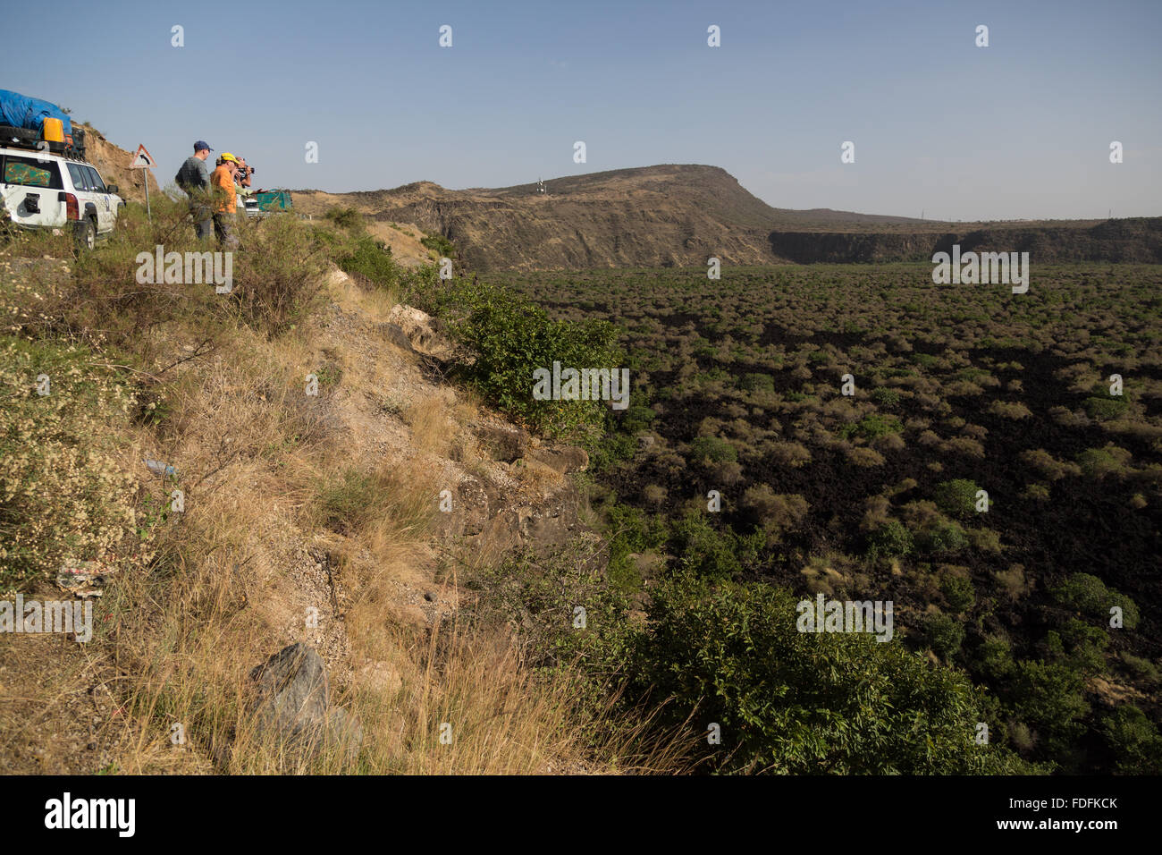 Travellers look out over a recent lava flow which has been colonised by low bushes in eastern Ethiopia Stock Photo