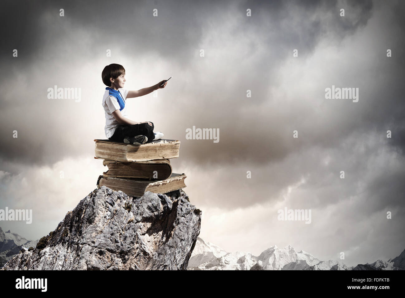 Image of little cute boy sitting on pile of books Stock Photo - Alamy