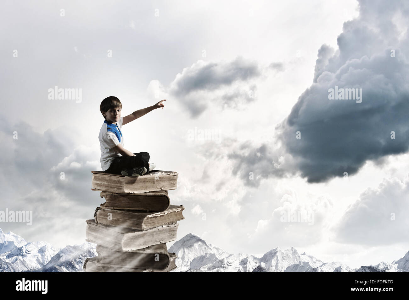 Image of little cute boy sitting on pile of books Stock Photo - Alamy