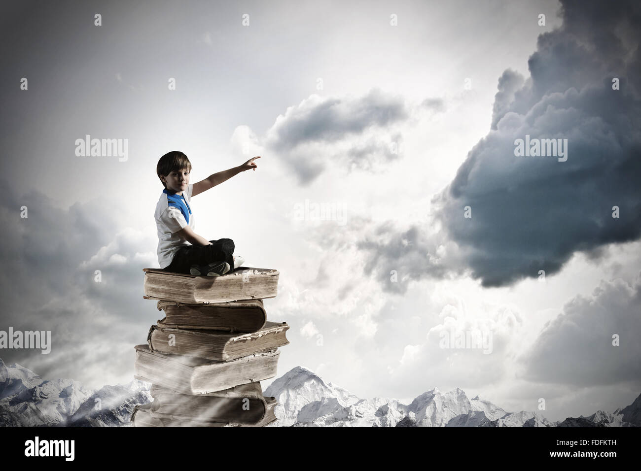 Image of little cute boy sitting on pile of books Stock Photo - Alamy