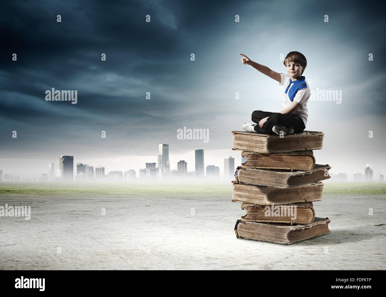 Image of little cute boy sitting on pile of books Stock Photo - Alamy