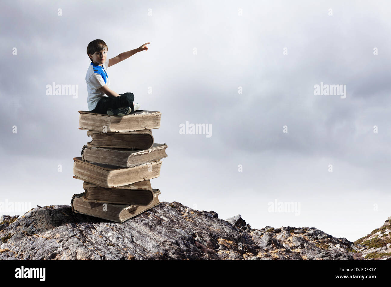Image of little cute boy sitting on pile of books Stock Photo - Alamy