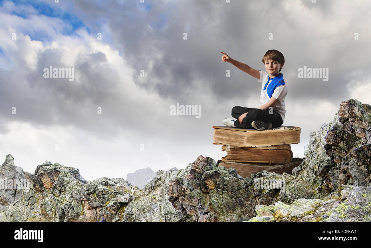 Image of little cute boy sitting on pile of books Stock Photo - Alamy