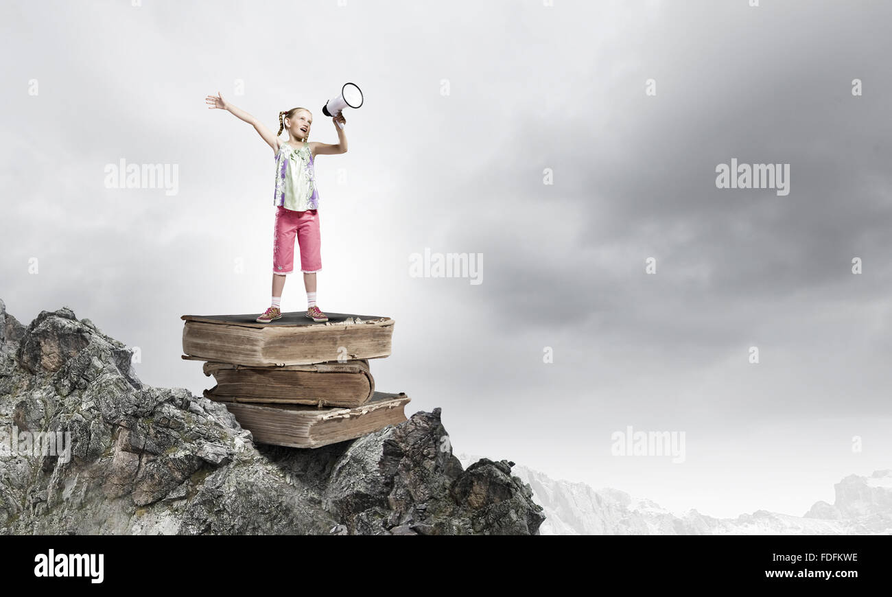 Image of cute school girl standing on pile of books Stock Photo - Alamy