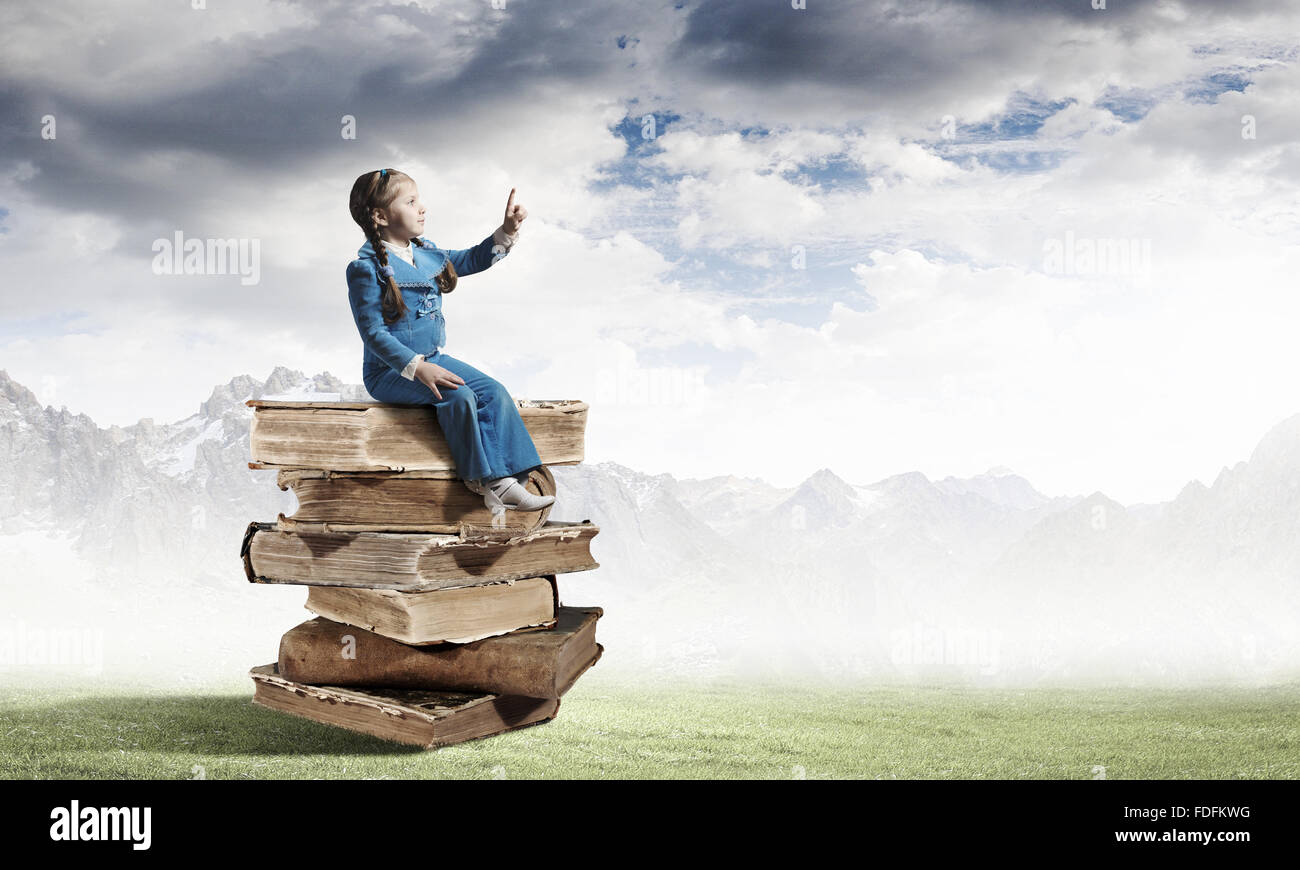 Image of cute school girl in sitting on pile of books Stock Photo - Alamy