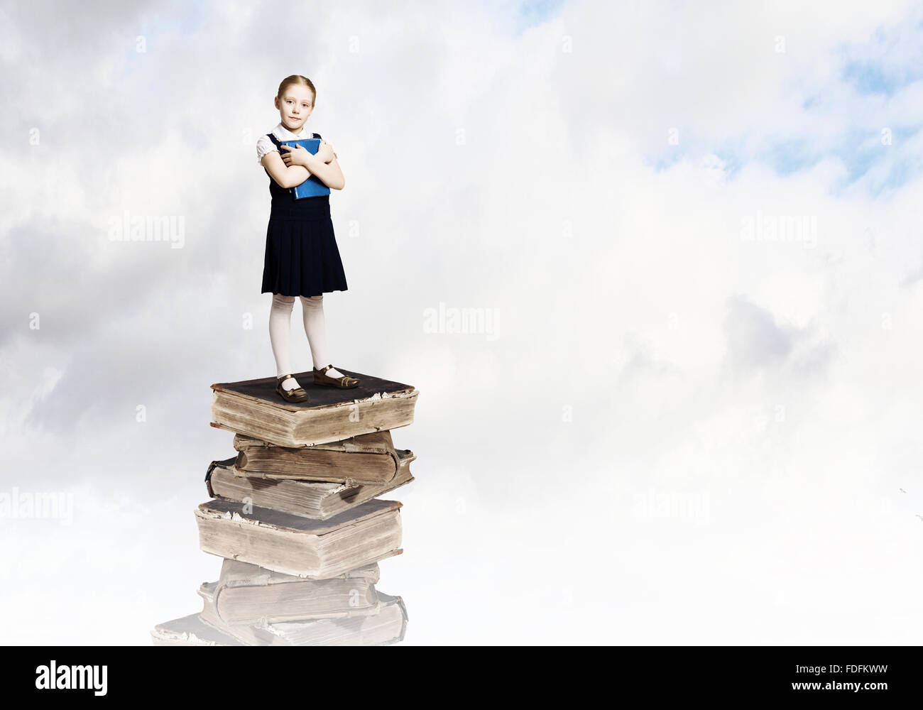 Image of cute school girl standing on pile of books Stock Photo - Alamy