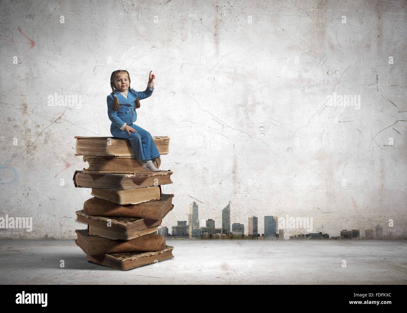 Image of cute school girl in sitting on pile of books Stock Photo - Alamy