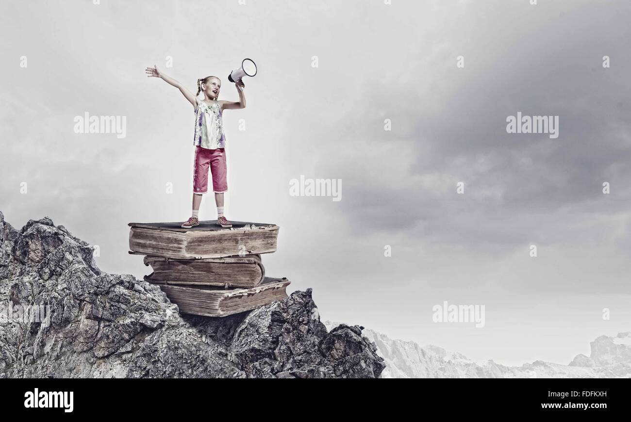 Image of cute school girl standing on pile of books Stock Photo - Alamy